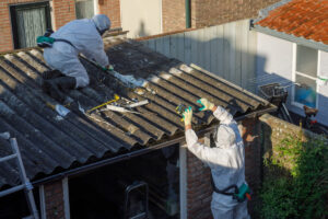 Professional asbestos removal. Men in protective suits are removing asbestos cement corrugated roofing